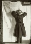 Young girl standing inside with her hands behind her head. EW Carter photo ca. 1900 Glass negative: 5″x7″
