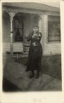 1910 ca. CAT Woman standing outside house holding a cat RPPC front